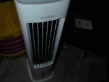 un climatiseur blanc posé par terre dans l'obscurité