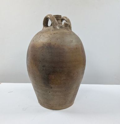 un grand vase marron posé sur une table blanche