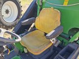 a green tractor with a yellow seat sitting in the grass