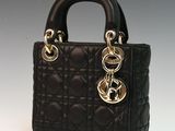black quilted handbag with gold hardware on a white background