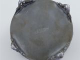 an antique silver plate on a white surface with a black background