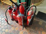 several fire extinguisors are lined up on a sidewalk
