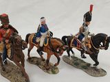 three figurines of men riding horses on snow covered ground