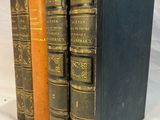 trois vieux livres posés l'un sur l'autre sur une surface blanche