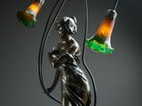 a bronze statue of a woman holding a lamp and a flower