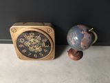 a clock and a globe on the floor next to a wall