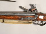 an old rifle with a wooden case and a knife on a white surface