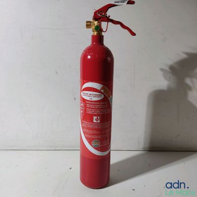 un extincteur rouge posé sur une surface blanche