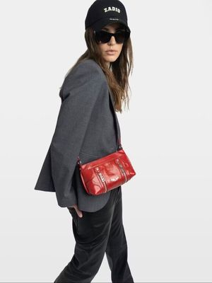 the woman is walking with a red purse and a black hat