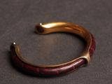 an image of a red and gold bracelet on a black surface