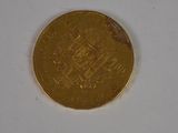 a gold coin on a white surface with a white background