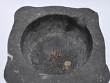 a black stone ashtray with a small piece of ash in it