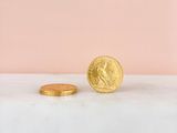 a gold coin sitting on top of a marble counter next to a pink wall
