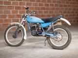 a blue dirt bike parked in front of a brick wall