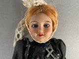 a doll that is wearing a dress and a hat