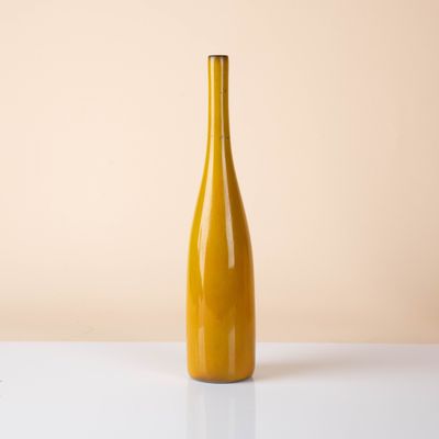 a yellow bottle of wine on a white table against a beige background