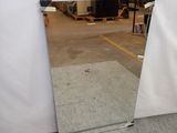 un miroir posé par terre devant un mur blanc