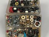 a box of assorted buttons and screws on a white surface