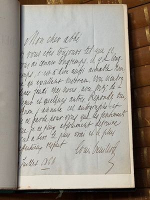 un livre ouvert, sur lequel est inscrit un poème manuscrit, posé sur une table