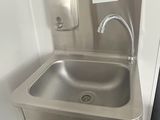 a stainless steel sink in the corner of a bathroom
