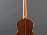 an acoustic guitar on a stand against a gray background