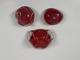 four pieces of red glass sitting on top of a white surface