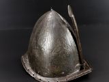 a silver helmet with a spoon in it on a black surface