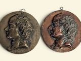 two bronze medallions of a woman and a man on a white background