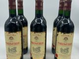 four bottles of wine are lined up on a white surface