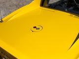 the front end of a yellow car with the emblem of a car on it