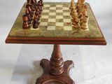 un jeu d'échecs ancien posé sur un socle surmonté d'un plateau en marbre
