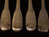four silver spoons with designs on them on a black surface