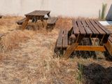 deux tables de pique-nique en bois au milieu d'un champ