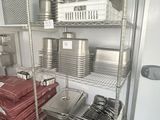 a kitchen with a stove, microwave, and a rack with pots and pans on it