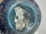 a person holding a blue glass ball with a face in it