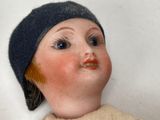 a close up of a doll wearing a hat and sweater