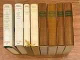 Plusieurs vieux livres sont alignés sur une table en bois