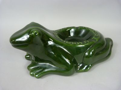 un cendrier en forme de grenouille verte posé sur une table blanche