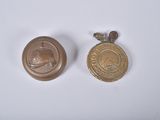deux petites médailles d'or sont posées l'une à côté de l'autre sur une surface blanche