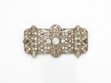 un gros plan d'une broche en diamant et argent sur fond blanc