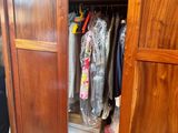 a large wooden cabinet with a bunch of clothes in it
