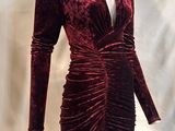 Le mannequin porte une robe en velours rouge à manches longues.