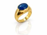 gros plan d'une bague en or avec une pierre bleue