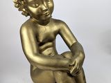 statue en or représentant un garçon assis par terre, les mains posées sur les genoux
