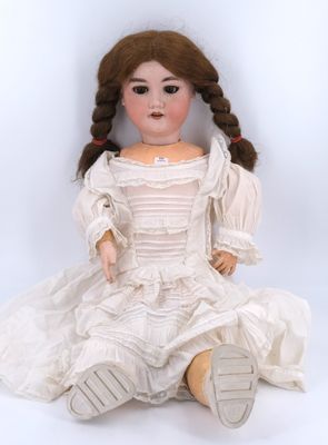 an old doll sitting on the ground with a white dress on