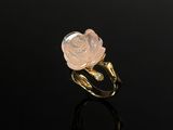 a gold ring with a pink rose on a black surface