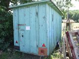 a small blue shed sitting in the middle of a field