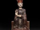 une statue en bois représentant un homme assis, coiffé d'une couronne