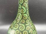 a green and brown vase with swirl designs on it