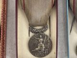 three medals in a box on a table with a pair of scissors